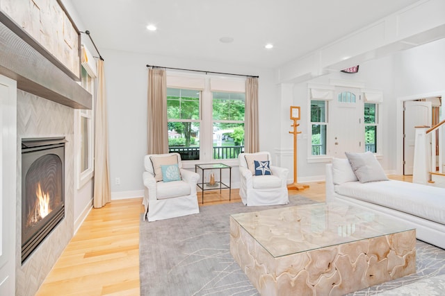 living room with a tiled fireplace and light hardwood / wood-style floors