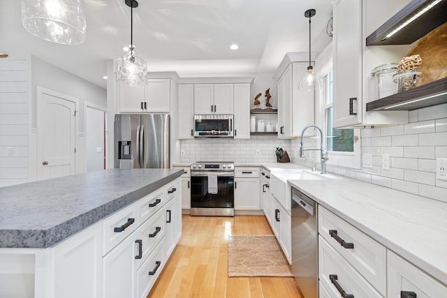 kitchen with decorative backsplash, stainless steel appliances, pendant lighting, white cabinets, and a center island