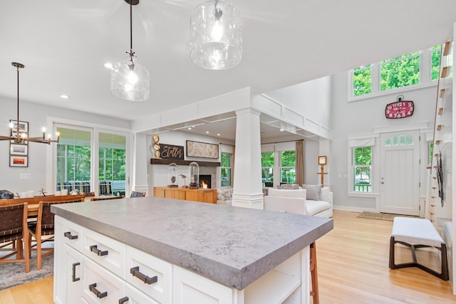 kitchen with a kitchen island, white cabinets, pendant lighting, and light hardwood / wood-style floors