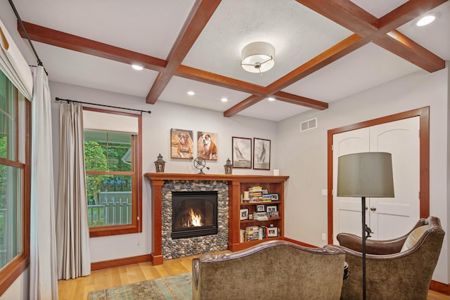 living room featuring beamed ceiling, a fireplace, light hardwood / wood-style flooring, and coffered ceiling