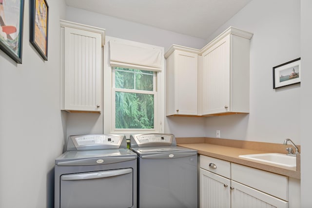 laundry area featuring washer and dryer, cabinets, and sink