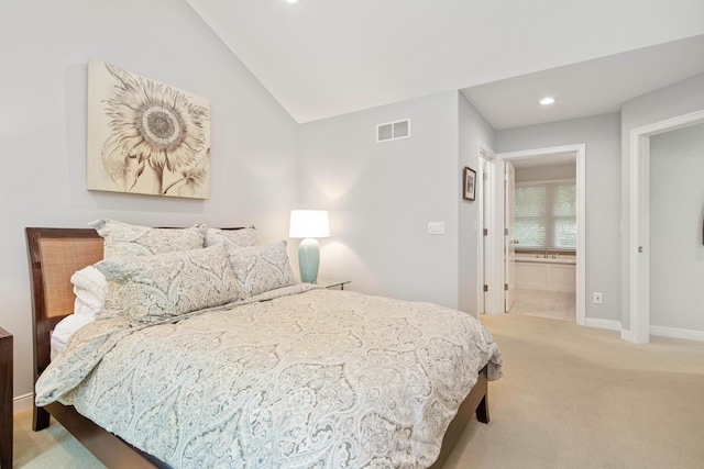 bedroom featuring ensuite bath, light colored carpet, and lofted ceiling