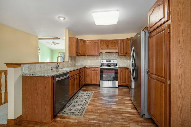 kitchen featuring sink, dark hardwood / wood-style floors, stainless steel appliances, light stone countertops, and decorative backsplash