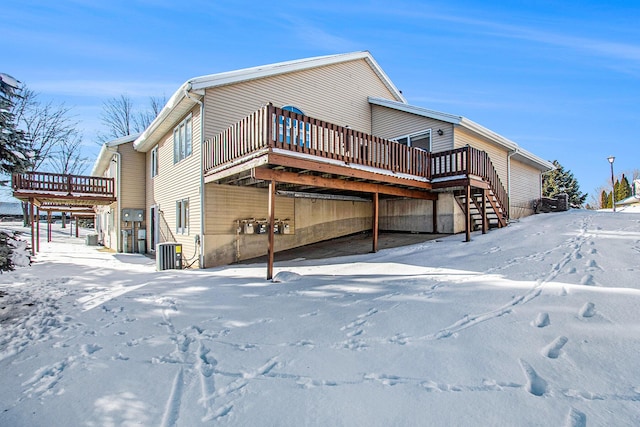 snow covered property with a wooden deck and central AC