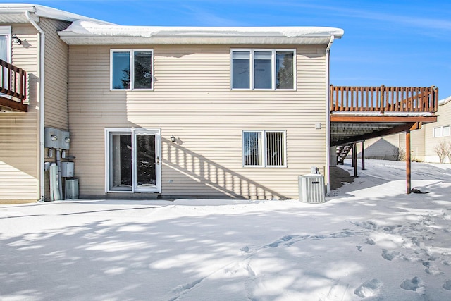 snow covered property with central AC unit and a deck