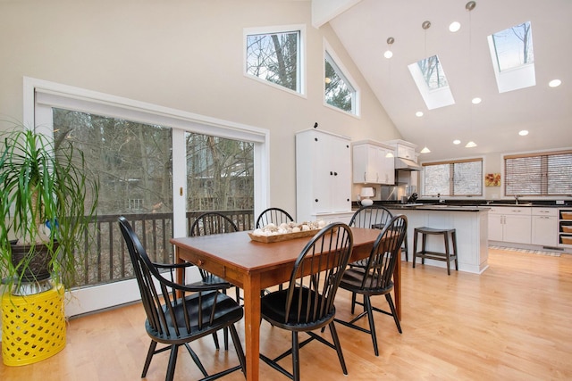 dining room featuring light hardwood / wood-style floors, a healthy amount of sunlight, high vaulted ceiling, and a skylight