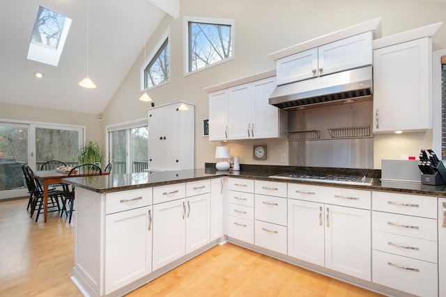 kitchen featuring a skylight, white cabinets, high vaulted ceiling, and stainless steel gas cooktop