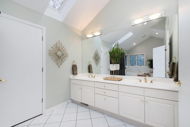 bathroom featuring a bathtub, vaulted ceiling with skylight, vanity, and tile patterned flooring