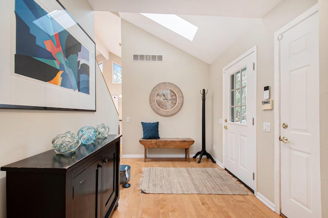 foyer entrance with wood-type flooring and vaulted ceiling with skylight