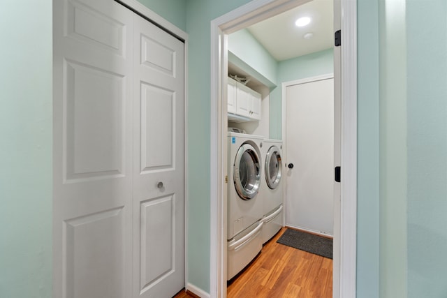 laundry area with light hardwood / wood-style flooring, cabinets, and independent washer and dryer