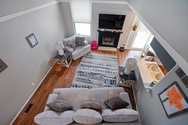 living room with hardwood / wood-style floors, ornamental molding, and a tiled fireplace