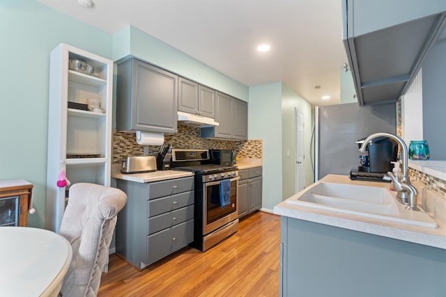 kitchen with tasteful backsplash, stainless steel gas range, sink, light hardwood / wood-style flooring, and gray cabinets