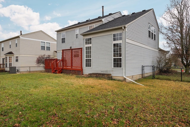 rear view of property featuring central AC unit, a wooden deck, and a lawn