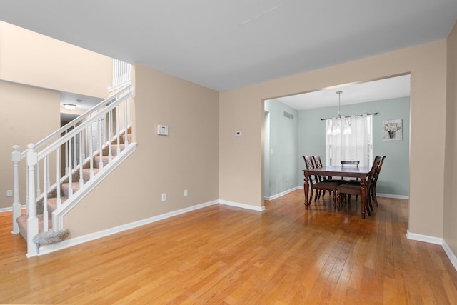 dining space with hardwood / wood-style floors and a chandelier