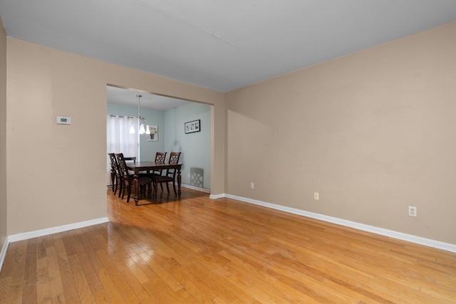 spare room with hardwood / wood-style flooring and a chandelier