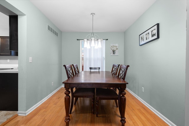 dining room with light hardwood / wood-style floors and a chandelier