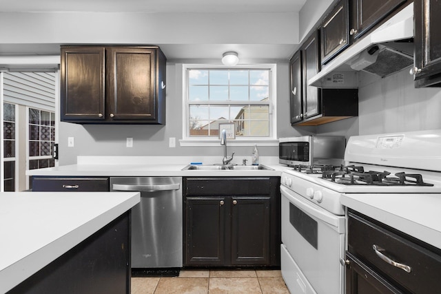 kitchen with dark brown cabinetry, sink, light tile patterned flooring, and stainless steel appliances