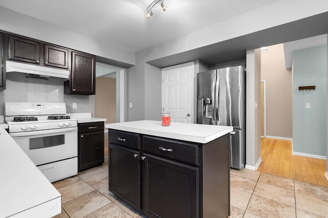 kitchen featuring white gas range, light tile patterned floors, a kitchen island, and stainless steel refrigerator with ice dispenser