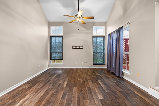 unfurnished room featuring ceiling fan, dark hardwood / wood-style flooring, a towering ceiling, and a healthy amount of sunlight