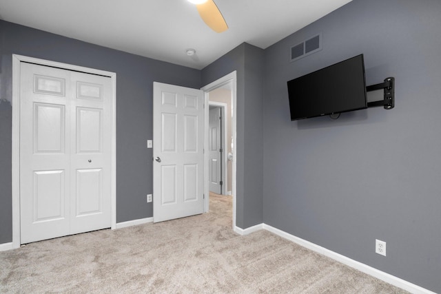 unfurnished bedroom with ceiling fan, a closet, and light carpet