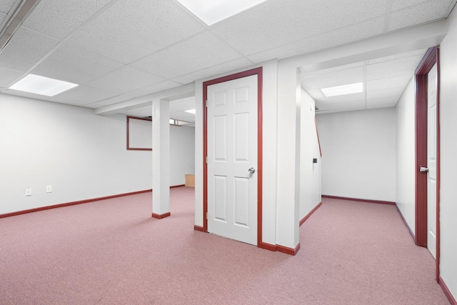 basement with a paneled ceiling and light carpet