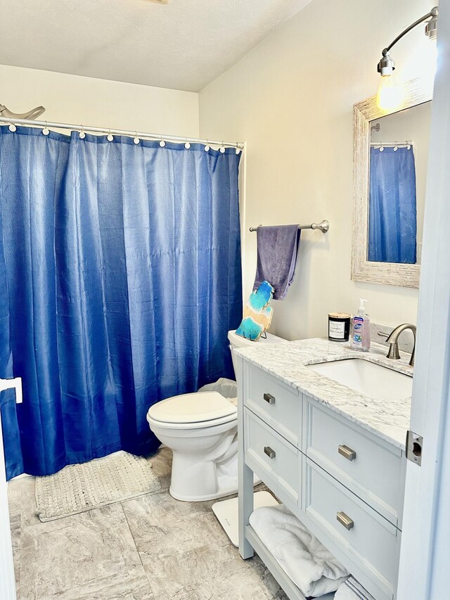 bathroom featuring curtained shower, vanity, and toilet