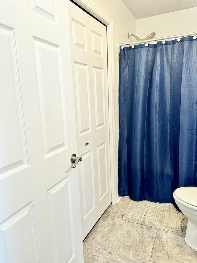 bathroom featuring walk in shower and toilet