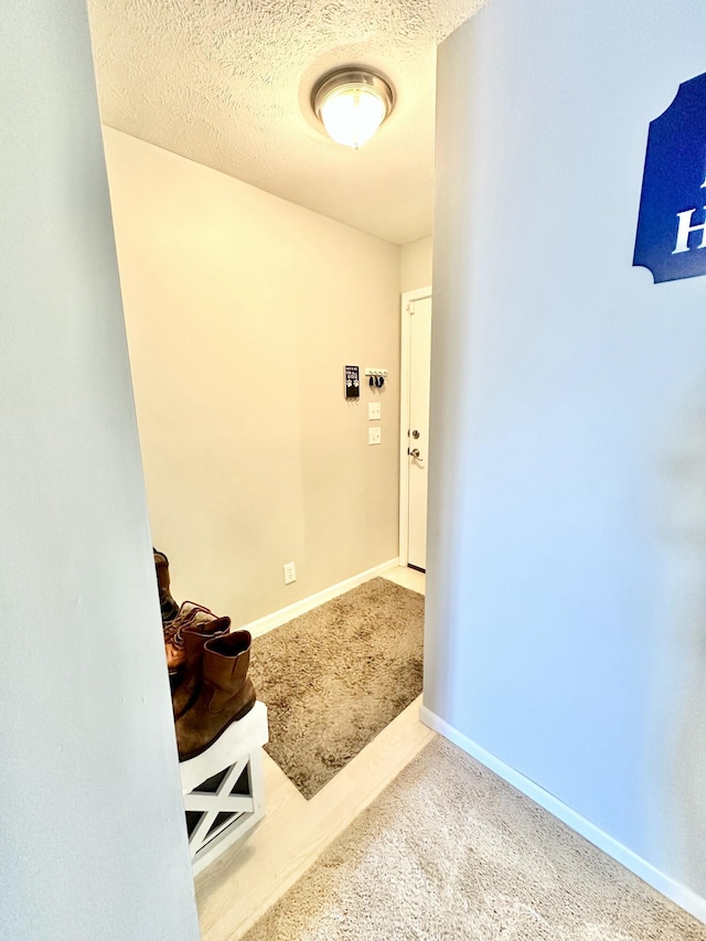 hall with carpet and a textured ceiling