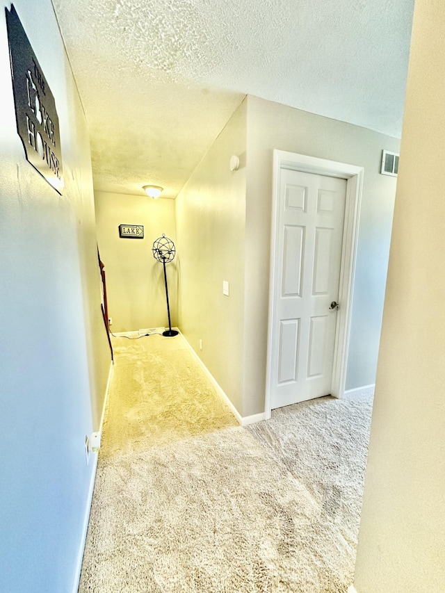 hallway featuring a textured ceiling and carpet floors