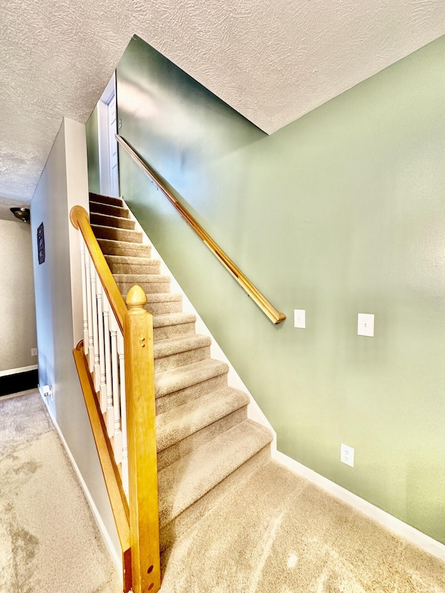 staircase with carpet floors and a textured ceiling