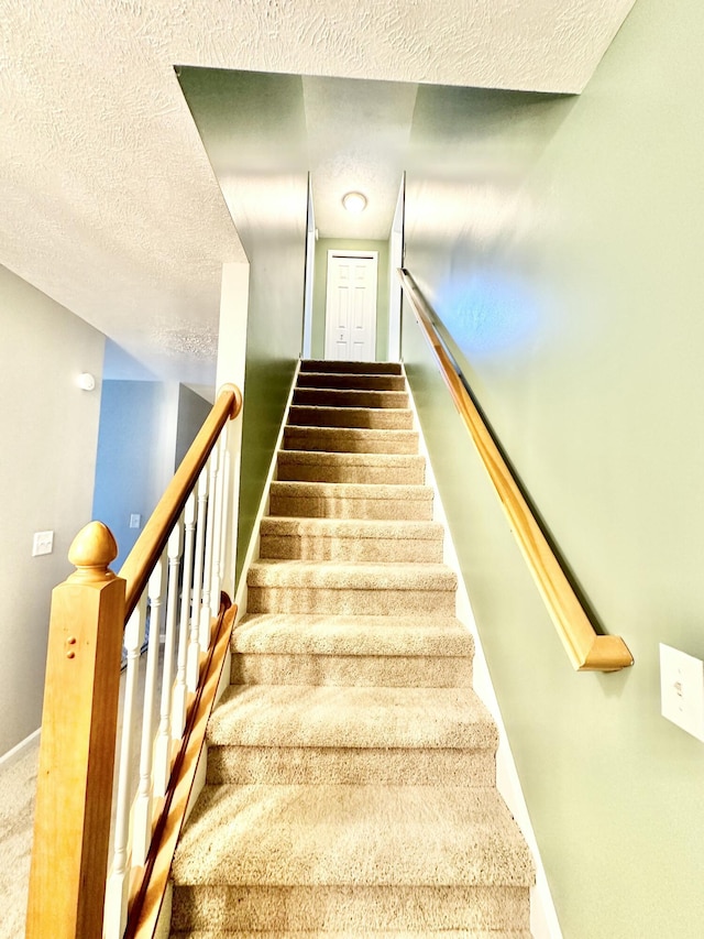 stairway featuring a textured ceiling