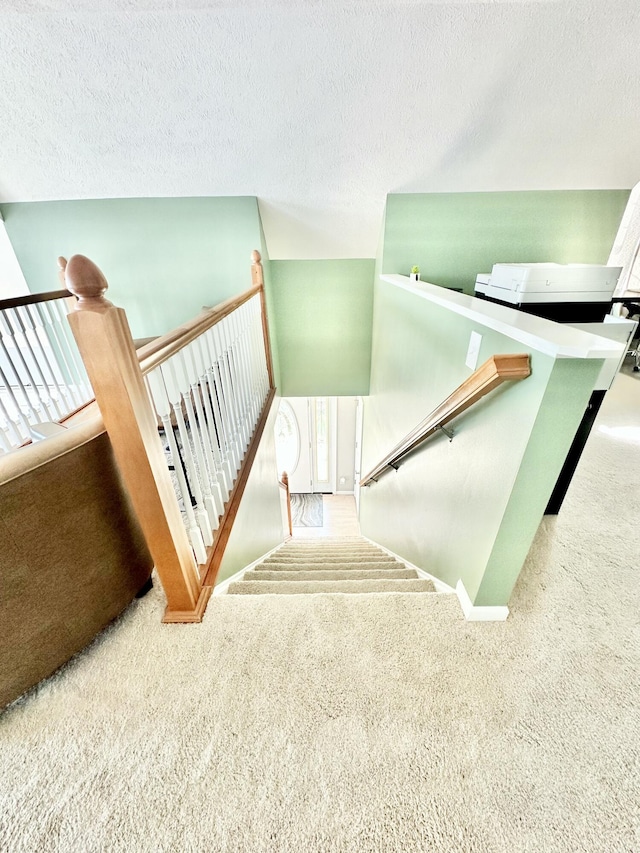 staircase with carpet and a textured ceiling