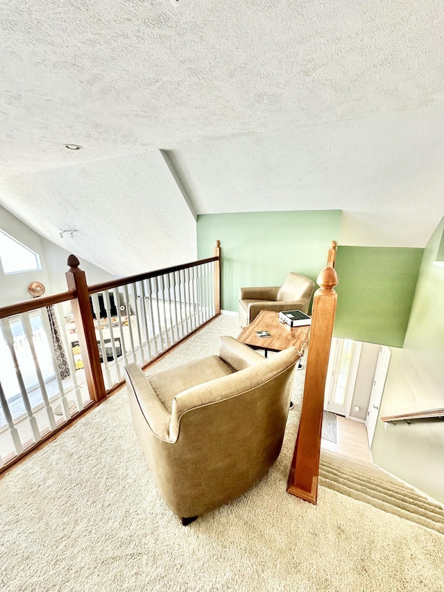 sitting room with a textured ceiling, carpet, and vaulted ceiling