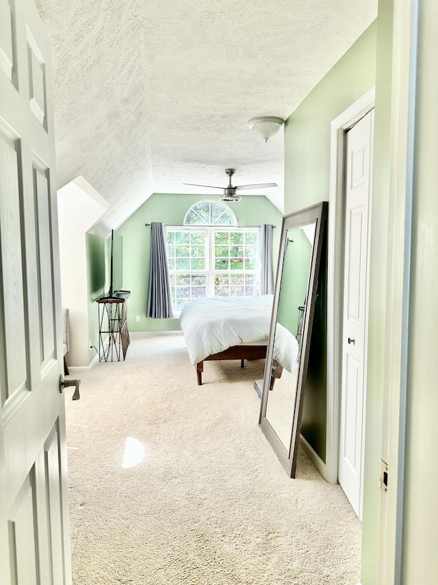 carpeted bedroom featuring ceiling fan, lofted ceiling, and a textured ceiling