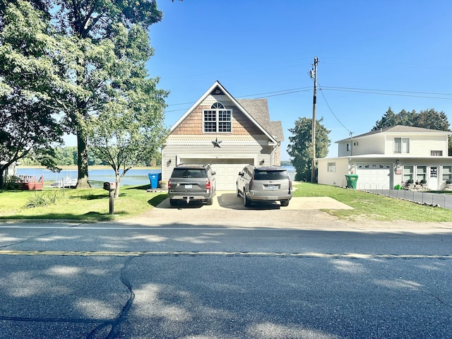 view of front of home featuring a front yard, a water view, and a garage