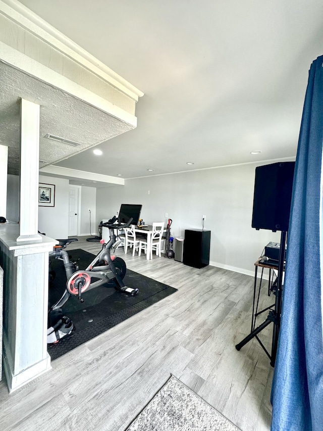 workout room featuring wood-type flooring and decorative columns