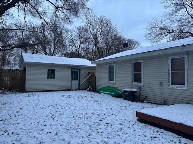 snow covered house featuring cooling unit