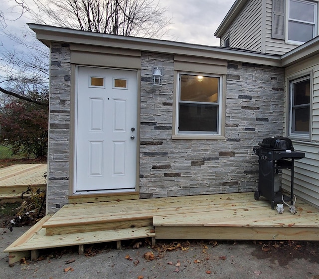 view of exterior entry featuring stone siding and a deck