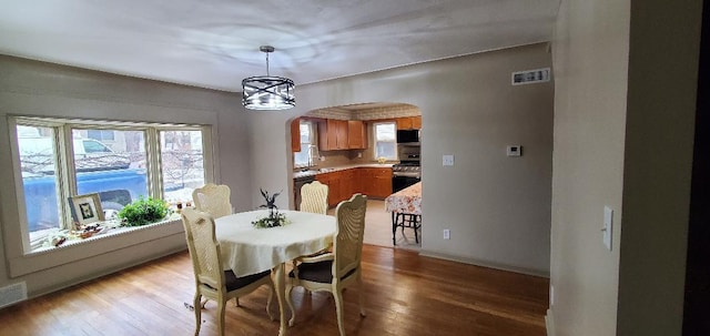 dining room featuring arched walkways, a notable chandelier, visible vents, baseboards, and light wood finished floors