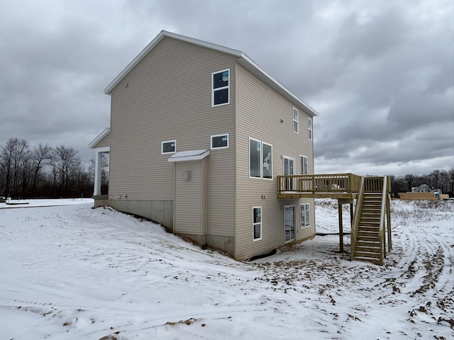 snow covered back of property with a deck