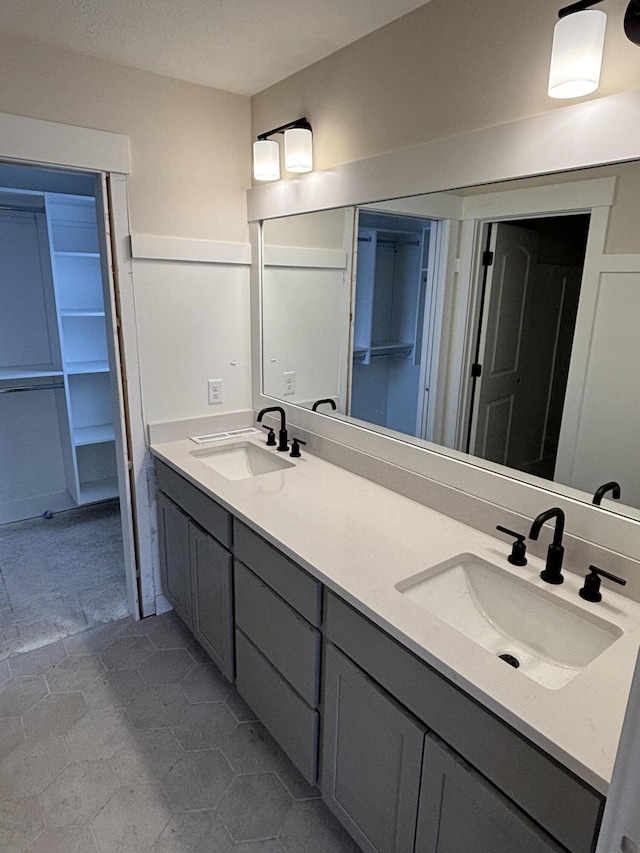 full bath featuring a textured ceiling, double vanity, and a sink