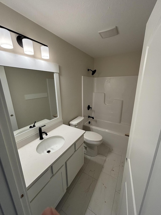 bathroom featuring a textured ceiling, toilet, bathing tub / shower combination, vanity, and marble finish floor