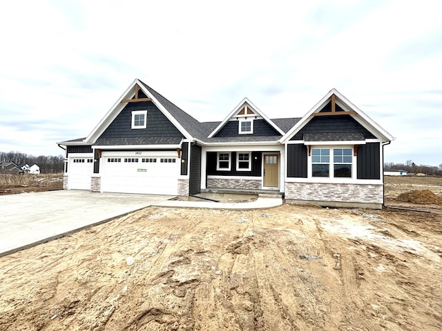 craftsman-style home with driveway, stone siding, and board and batten siding