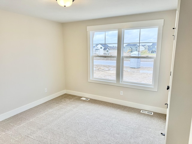 spare room featuring baseboards, visible vents, and carpet flooring