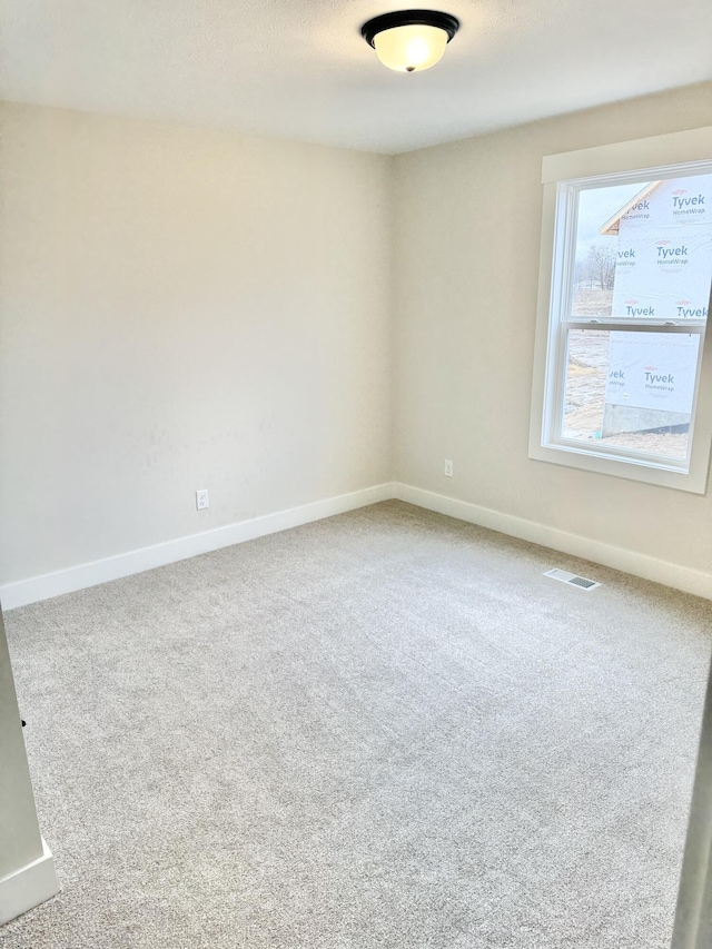 empty room with carpet floors, visible vents, and baseboards