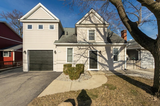 view of front of property with a chimney, driveway, roof with shingles, and an attached garage
