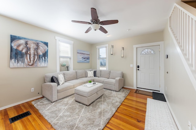 living room with visible vents, wood finished floors, stairway, and a ceiling fan