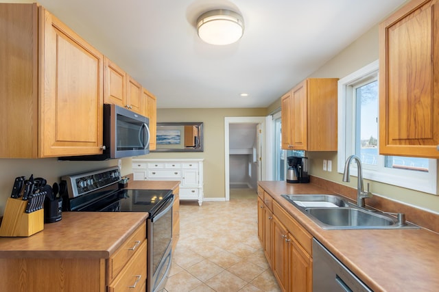 kitchen with a sink, baseboards, appliances with stainless steel finishes, and light tile patterned floors