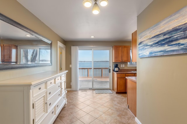 kitchen with baseboards, brown cabinetry, and light tile patterned floors