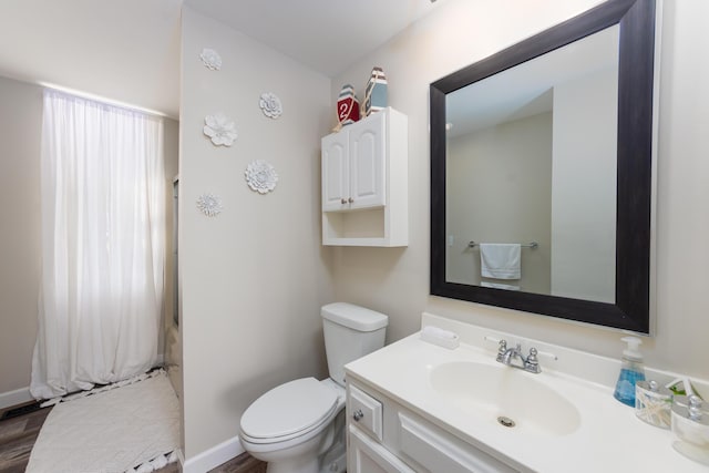 full bath featuring toilet, vanity, and baseboards